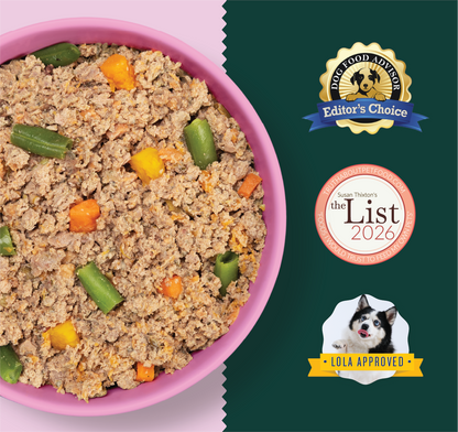 Ground meat puppy food with green beans and diced carrots in a pink bowl, next to product packaging.